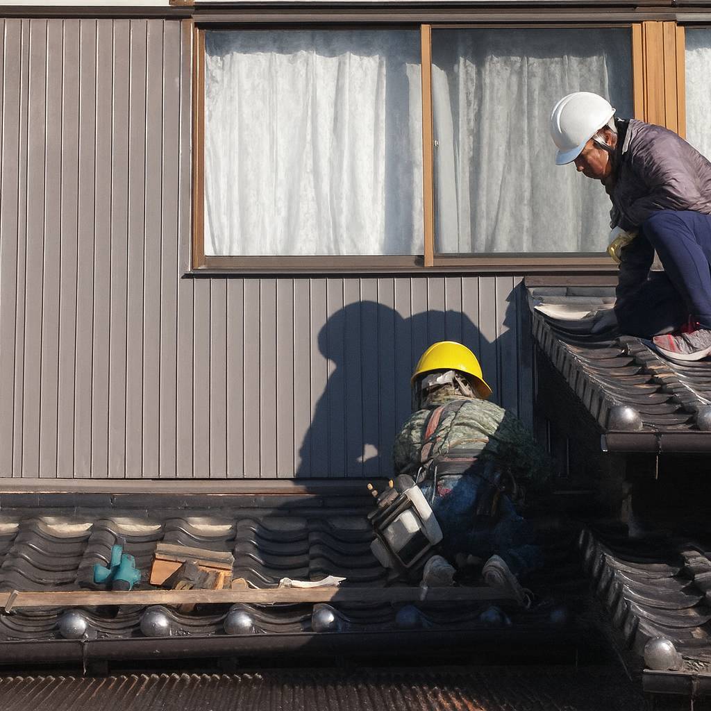 伊万里市の和風住宅で、瓦屋根の漆喰や谷板金を点検・修理している職人の様子